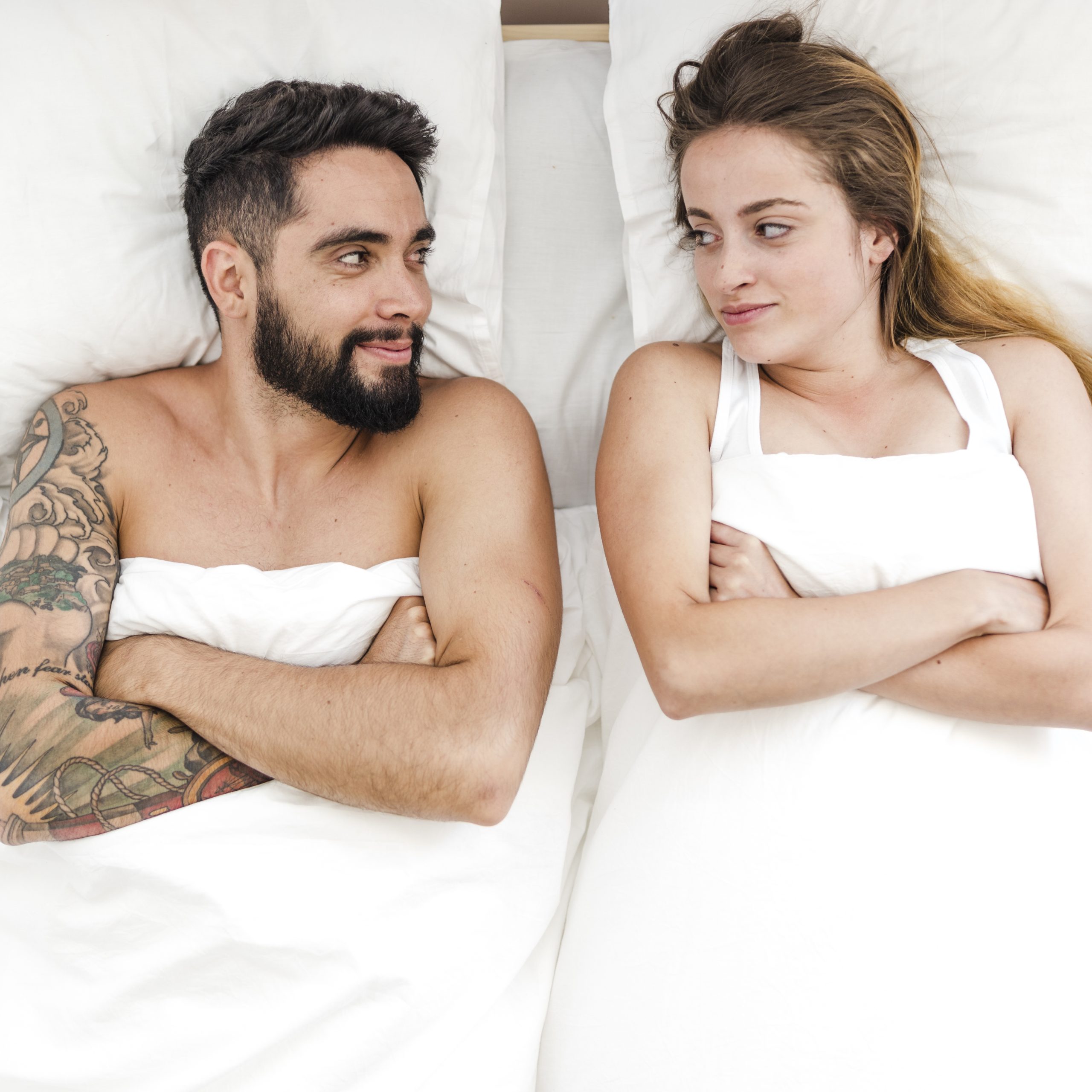 elevated-view-young-couple-lying-bed-looking-each-other